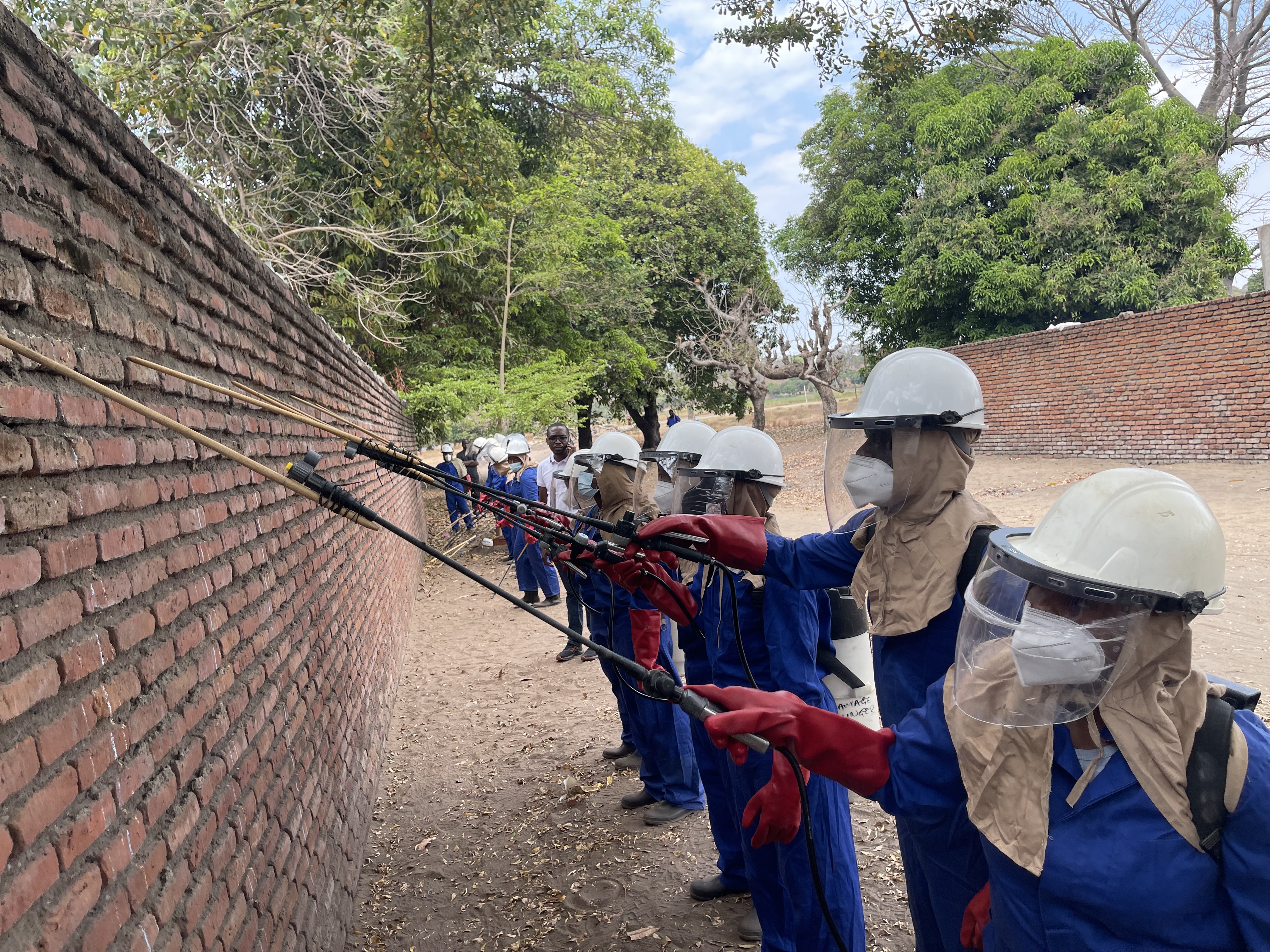 A line of spray operators practicing their spray technique on a brick wall. 